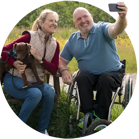 middle age man in wheelchair with wife enjoying the outdoors taking a selfie